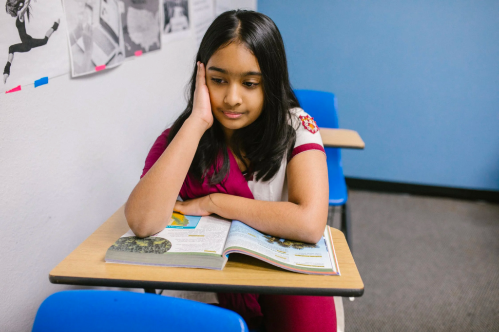 A shy, introverted girl stares at the ground while in class.
