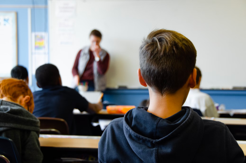 The back of a student’s head in a classroom.
