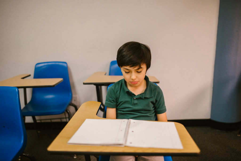 A child looks sadly at his notebook.