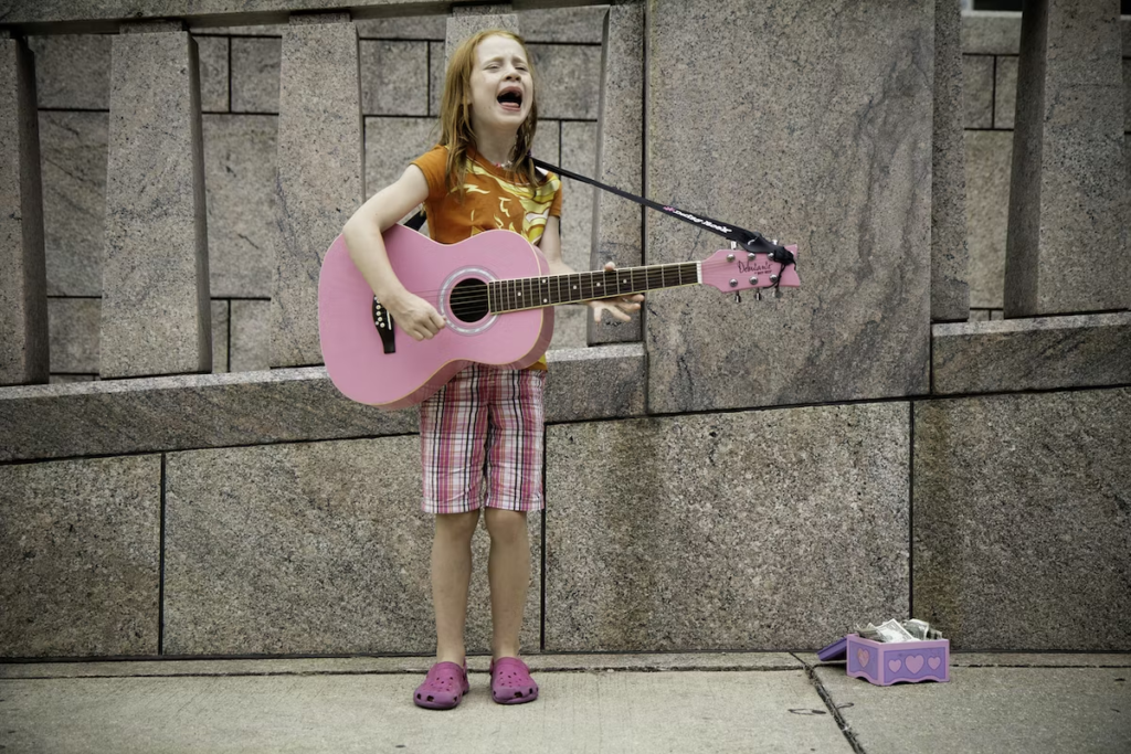 A young girl sings outdoors with a guitar