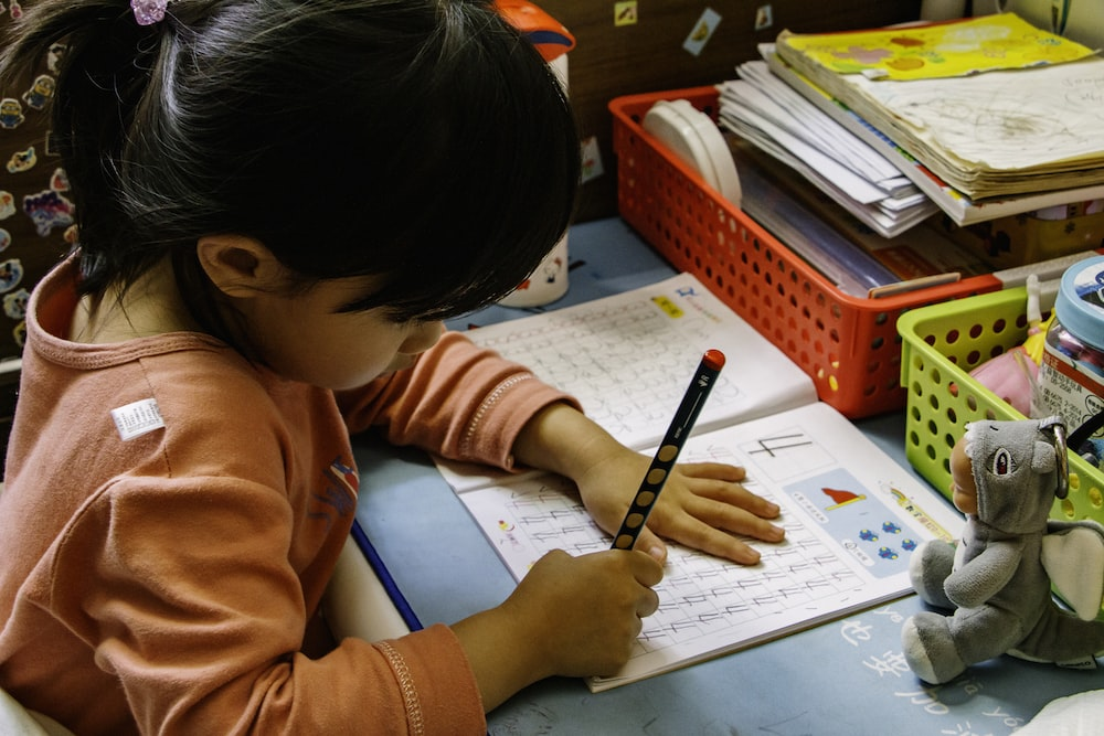 A girl is doing her homework on a notebook.
