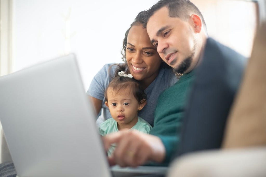  A couple is using a laptop with their child in the middle.