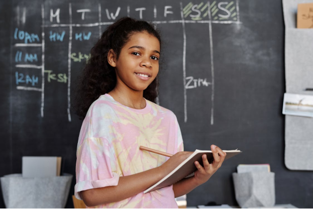 A kid holding a book and a pencil