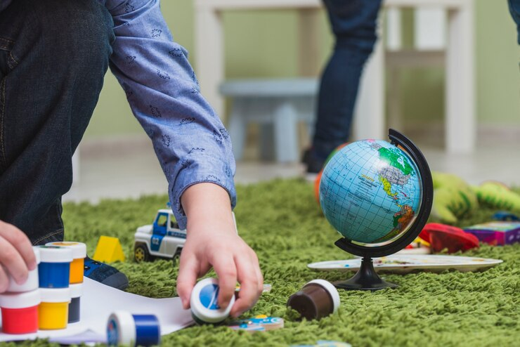 A child playing with paints on the floor, symbolizing creativity and eco-friendly practices in special education.